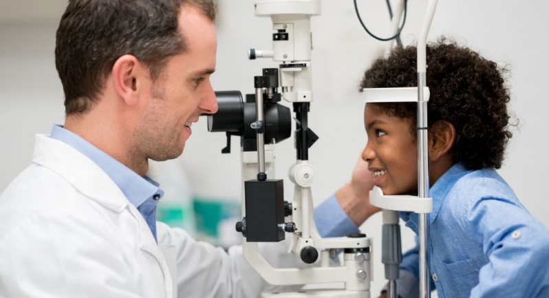 Médico examinando a visão de uma criança em aparelho de oftalmologia